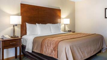 Camera d'hotel con una testiera in legno, due abat-jour, un telefono e una coperta marrone.
