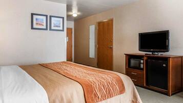 Habitación de hotel con cama, televisión, cómoda y dos cuadros en la pared.