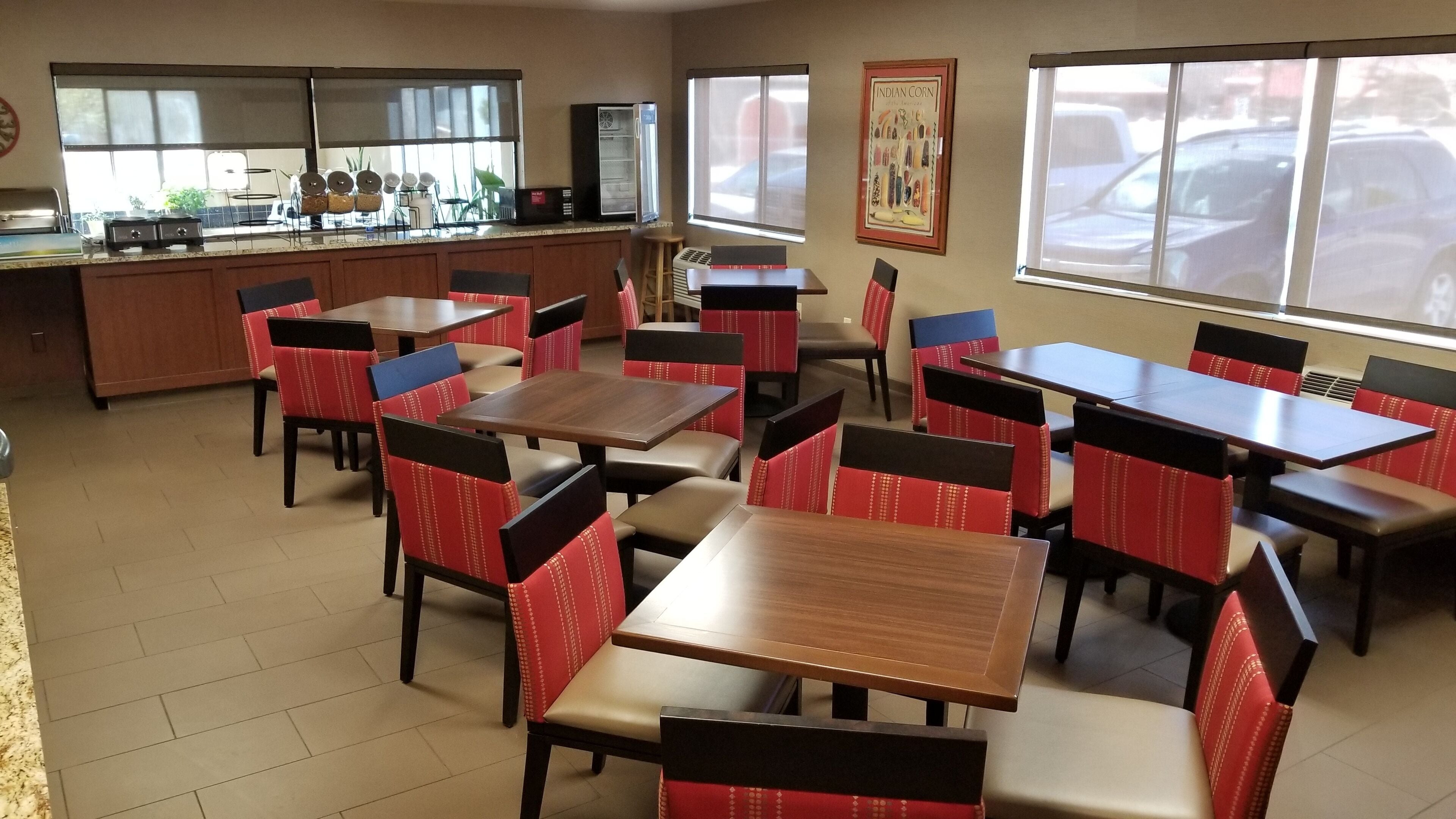 Ein Restaurant mit mehreren Tischen und Stühlen, einem Küchenbereich mit Geräten und großen Fenstern, die für natürliches Licht sorgen.