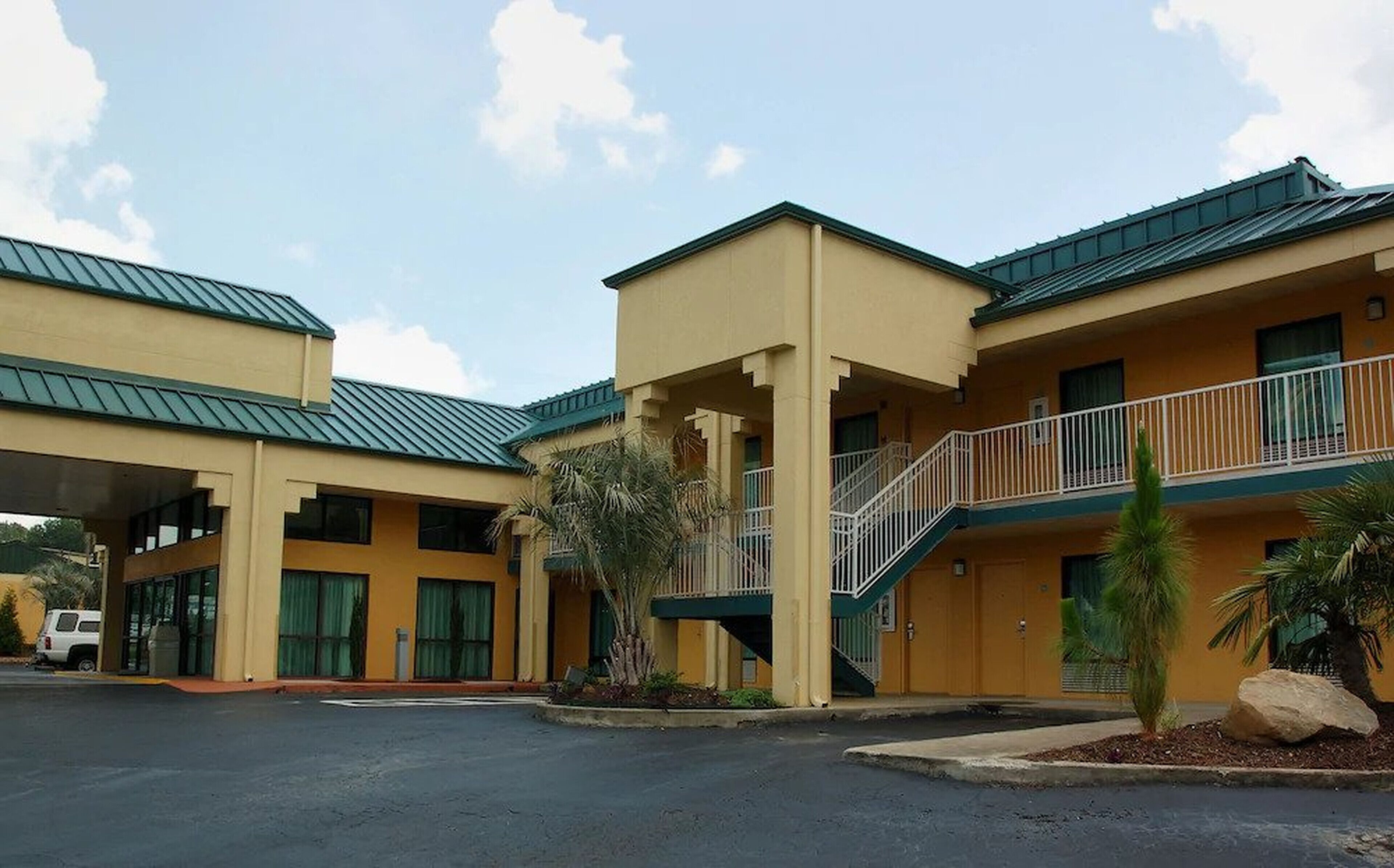 Um hotel de dois andares com telhado plano e entrada coberta.