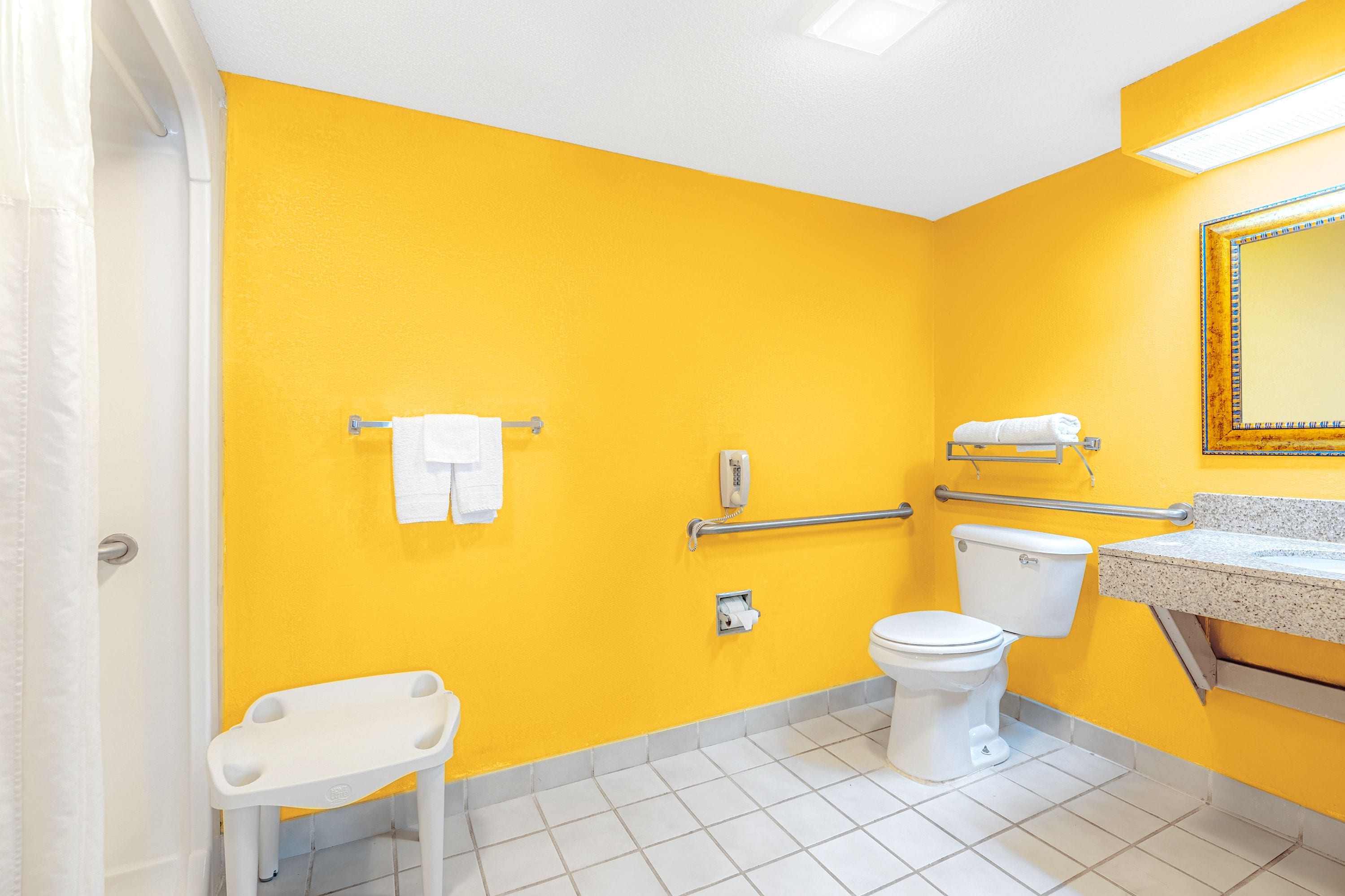 A bathroom with a yellow wall, white toilet, and a white sink with a mirror above it.