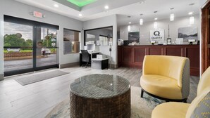 A hotel lobby with a reception desk, a glass coffee table, and a yellow armchair. - Quality Inn Adairsville - Calhoun South (Adairsville)