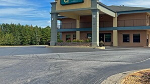 A hotel with a sign reading 'Quality Inn by Choice Hotels,' featuring a two-story structure with a covered entrance and a parking lot in front.