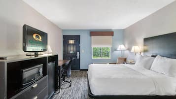 A hotel room with a bed, desk, chair, television, and a window with a view.