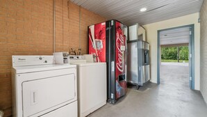 A laundry area with a Whirlpool washer, a Coca-Cola refrigerator, and a stainless steel oven. - Quality Inn Adairsville - Calhoun South (Adairsville)