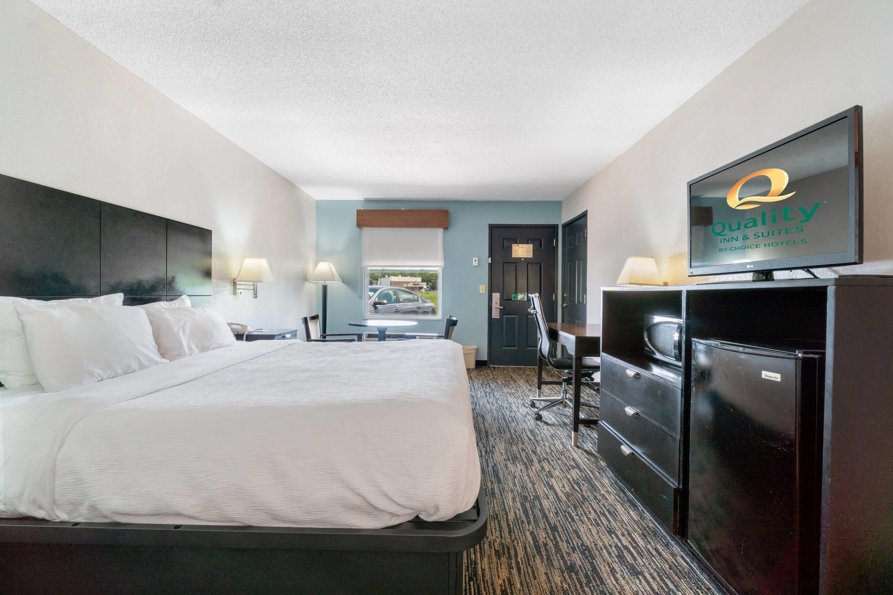 A hotel room with a bed, a desk, a television, and a wardrobe.