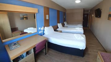 Quarto de hotel com duas camas, uma escrivaninha com cadeira, um espelho e uma lixeira pequena.