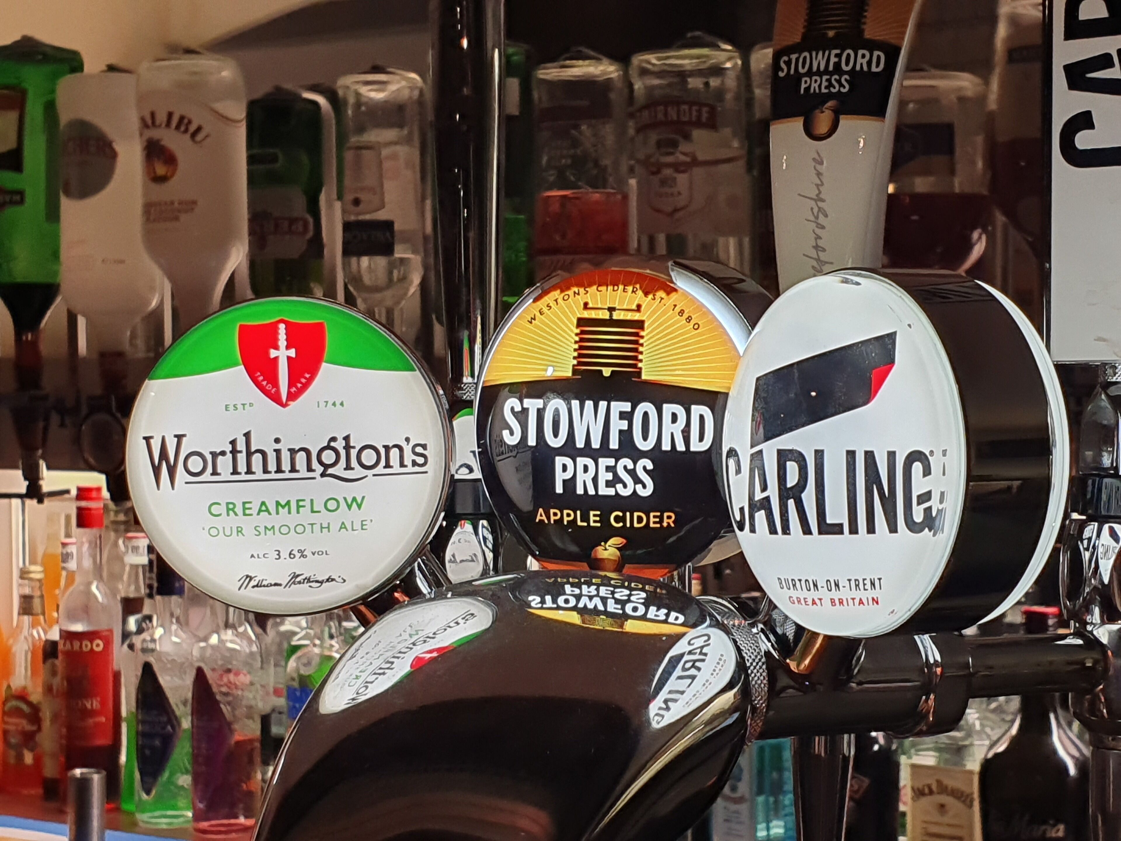 A bar tap area with various beer taps including Worthington's Creamflow, Stowford Press Apple Cider, and Carling.