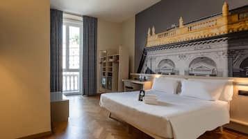 Una camera d'albergo con un letto grande, una scrivania, un armadio e vista su un edificio dalla finestra.