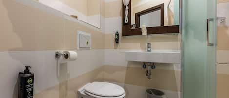 A modern bathroom with a bidet, toilet, sink, and a glass shower enclosure.