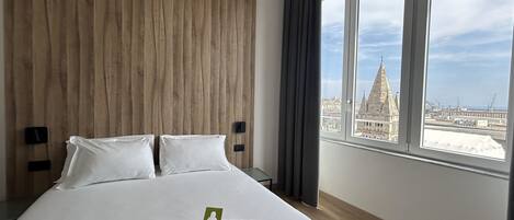 A hotel room with a large bed, a wooden headboard, and a view of a cityscape through large windows.