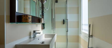 A modern bathroom with a large sink, a glass shower enclosure, and a mirror above the sink.