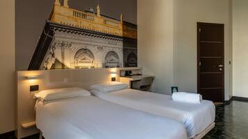 Habitación de hotel con dos camas, un escritorio y un mural grande de un edificio histórico.