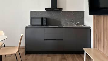 Una cocina moderna con microondas integrado, estufa y lavaplatos. Hay una zona de comedor con mesa y sillas.