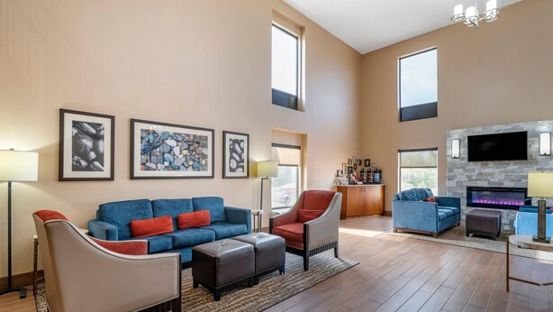 Ein geräumiges Wohnzimmer mit einem blauen Sofa, einem grauen Sessel und einem Kamin.