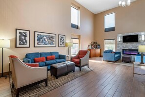 A spacious living room with a blue sofa, a grey armchair, and a fireplace. - Comfort Inn Lexington I-75 (Lexington)