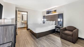 Une chambre d’hôtel avec un lit, une chaise, un bureau et une table de chevet.