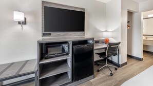A compact hotel room with a kitchenette, a flat-screen TV mounted on the wall, a desk with a chair, and a microwave. - Quality Inn Glasgow (Glasgow)