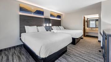 Ein Hotelzimmer mit zwei Betten, einem großen Gemälde an der Wand, einem Schreibtisch mit Spiegel und einem Teppichboden.