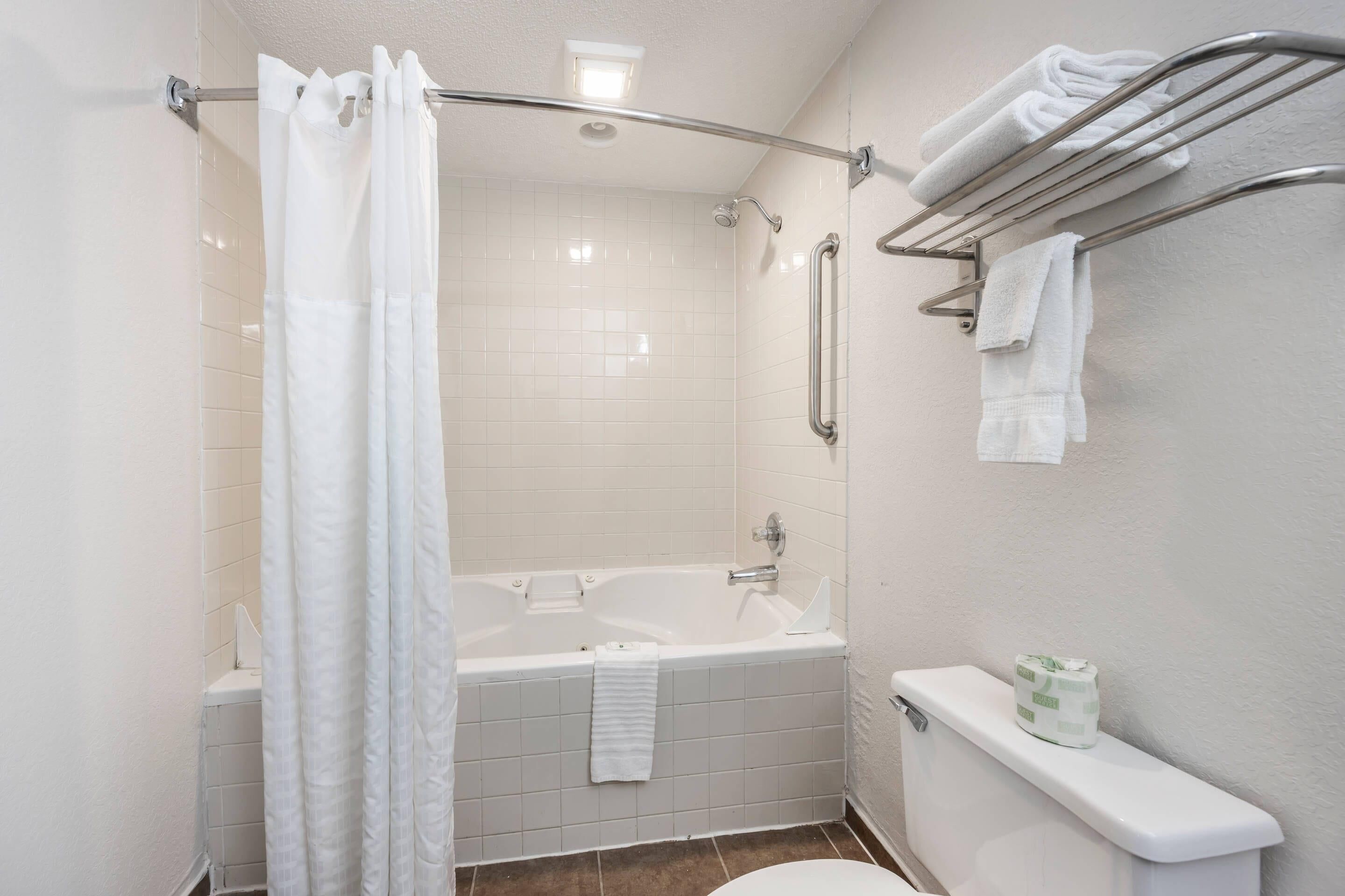 A bathroom with a bathtub, toilet, and a shower curtain.