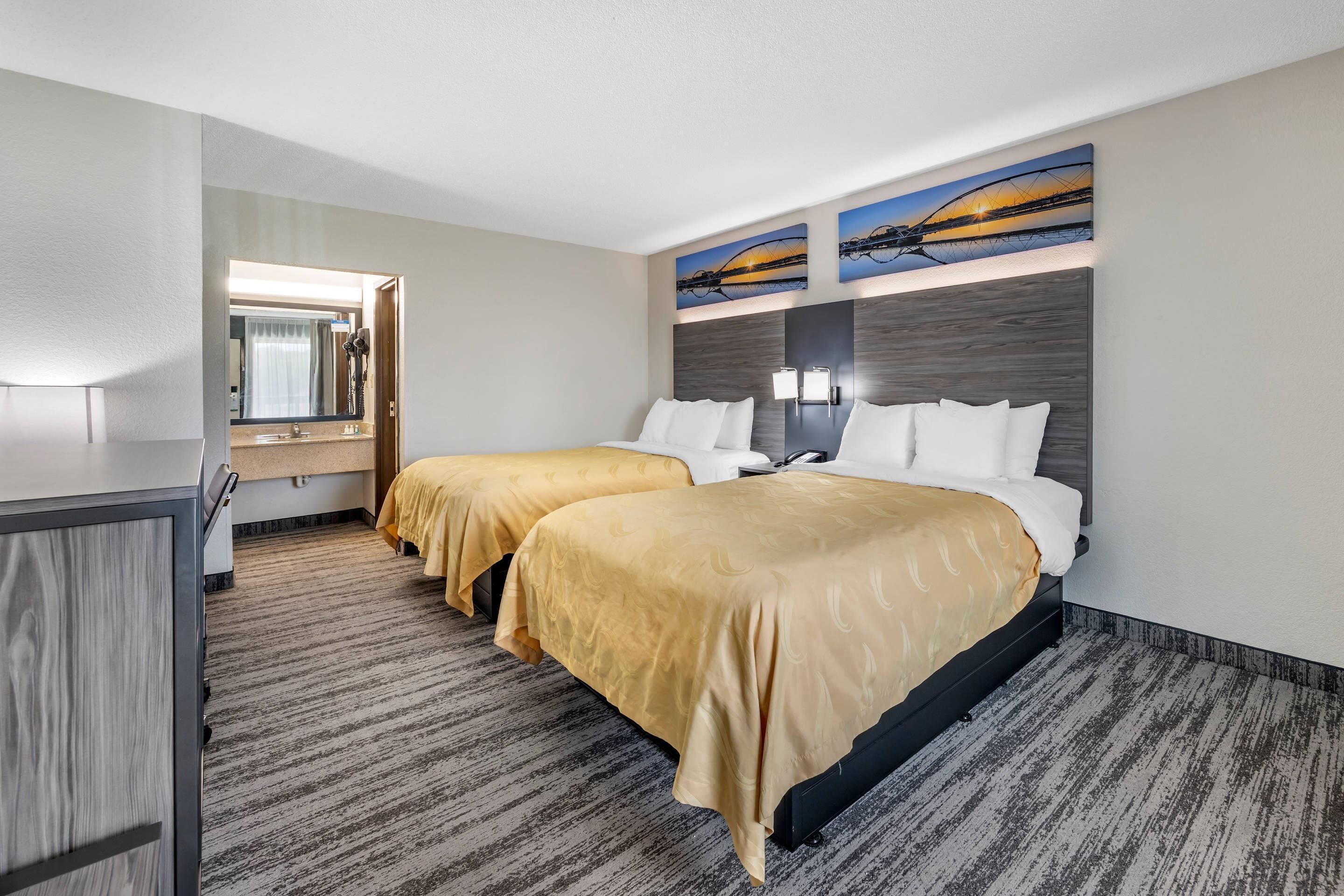 Une chambre d’hôtel avec deux lits, un bureau et une grande fenêtre.