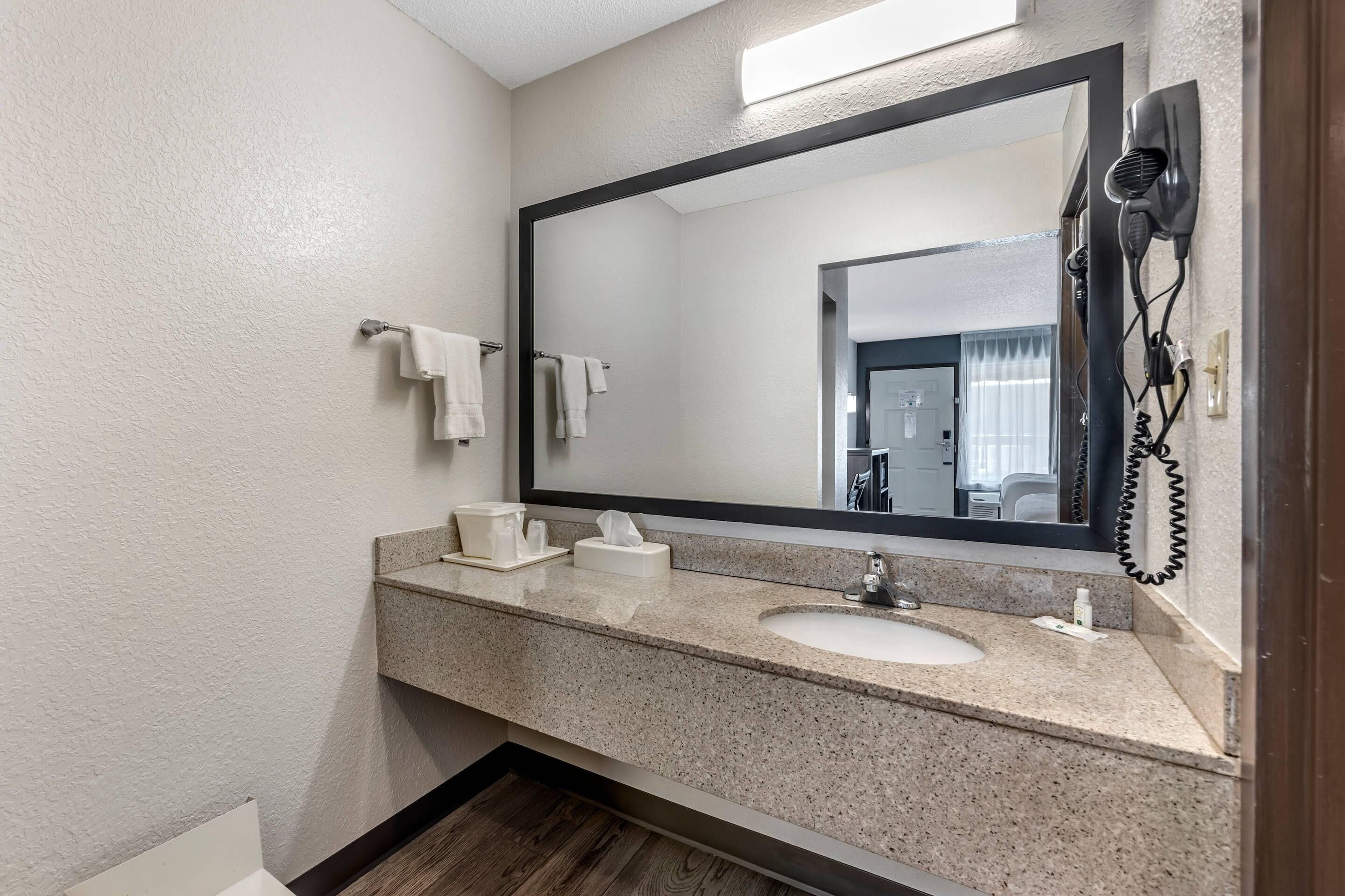 Un baño con un espejo grande, un secador de pelo, un lavabo y un perchero para toallas.