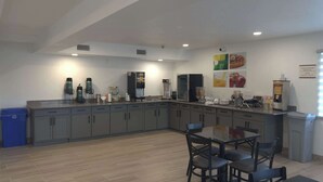 Uma cozinha moderna com armários cinza, uma ilha central com bancada e diversos eletrodomésticos, incluindo uma máquina de café e geladeira.