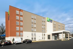 A multi-story hotel with a flat facade, a green and white sign indicating it's a Holiday Inn Express & Suites, and a parking lot with several cars. - Holiday Inn Express & Suites College Park-University Area by IHG (College Park)
