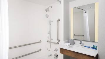 Un bagno moderno con doccia a ingresso facilitato, maniglie di sostegno, un lavandino con specchio e articoli da toilette.