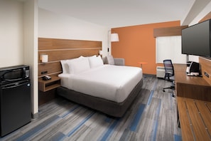Quarto de hotel com cama, escrivaninha, televisão, micro-ondas e frigorífico.