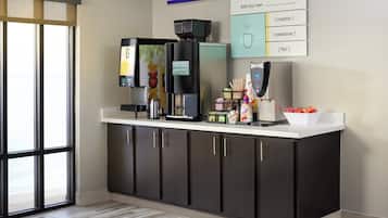 Una moderna area caffè con macchina da caffè, montalatte e cartello per aggiunta di panna, dolcificanti e aromatizzanti.