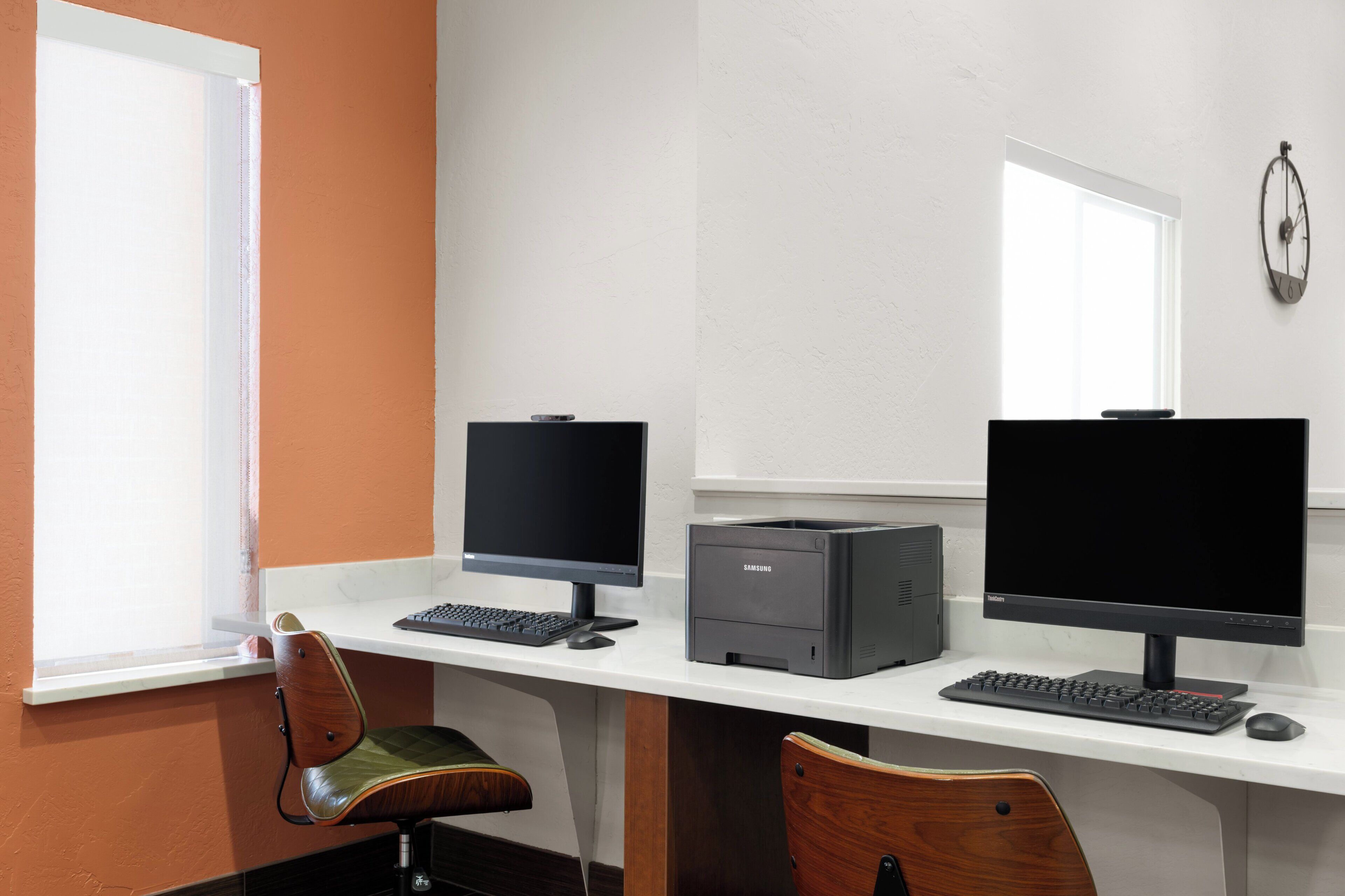 Un espacio de trabajo con dos monitores, una impresora y un teclado.