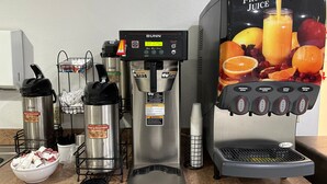 A coffee station with a Bunn coffee maker, a decaf coffee maker, and a fruit juice dispenser. - Baymont by Wyndham Omaha SW (Omaha)