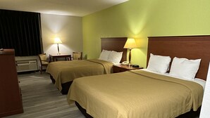 A hotel room with two beds, a desk, a chair, a lamp, and a heater. - Baymont by Wyndham Omaha SW (Omaha)