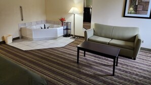Ein Hotelzimmer mit einer großen Badewanne, einem Sofa, einem kleinen Tisch und einer Lampe.