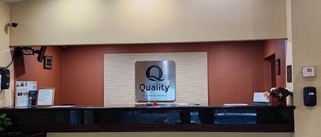 A hotel reception desk with a sign that reads "Quality by Choice Hotels".