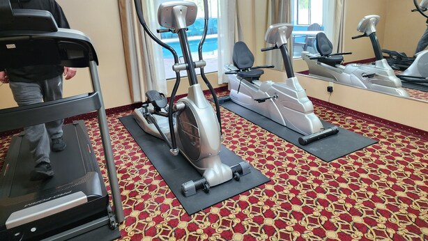 Ein Fitnessstudio mit Laufbändern, Ergometer und einer Spiegelwand.