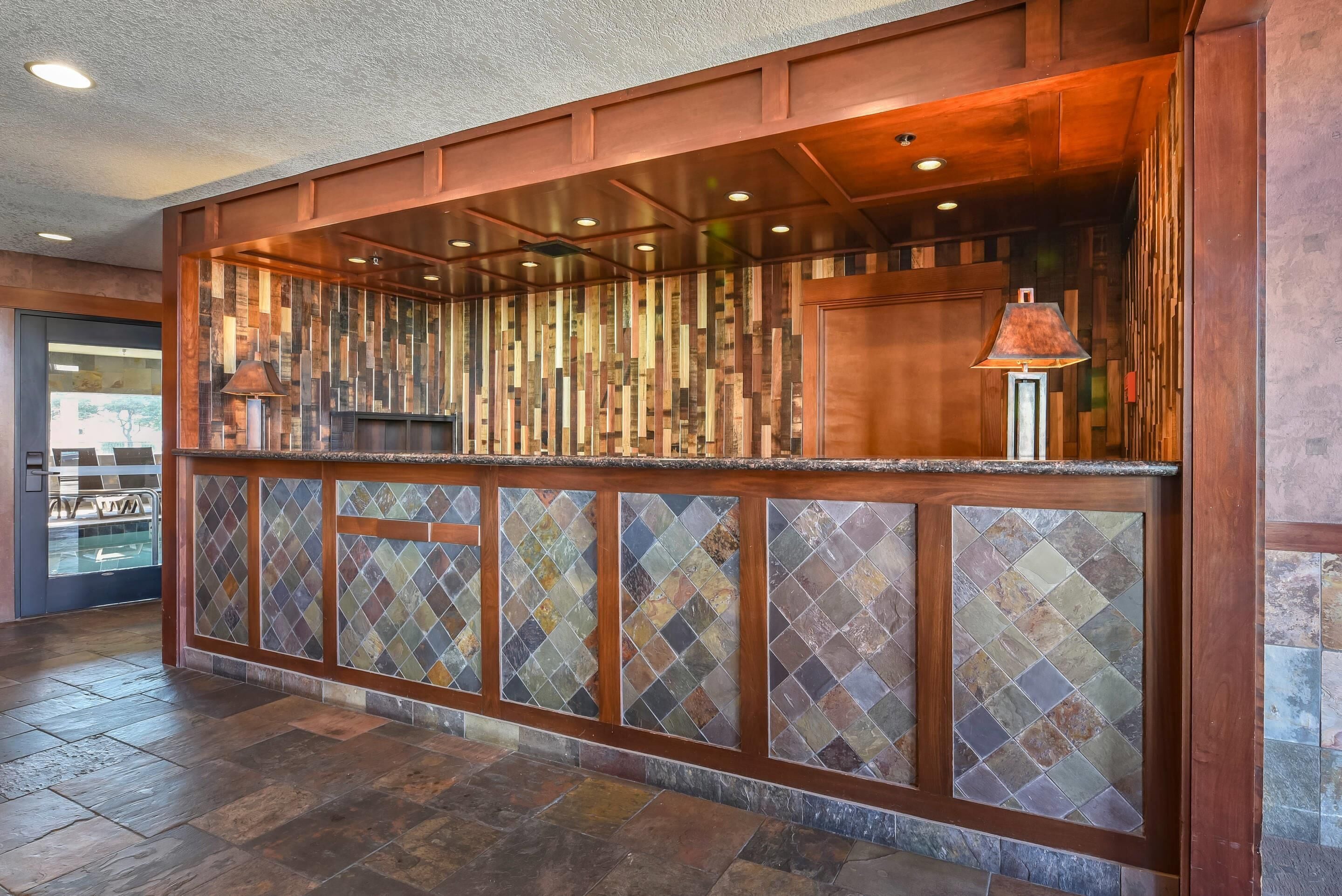 A reception area with a wooden counter, tiled panels, and a glass display case.