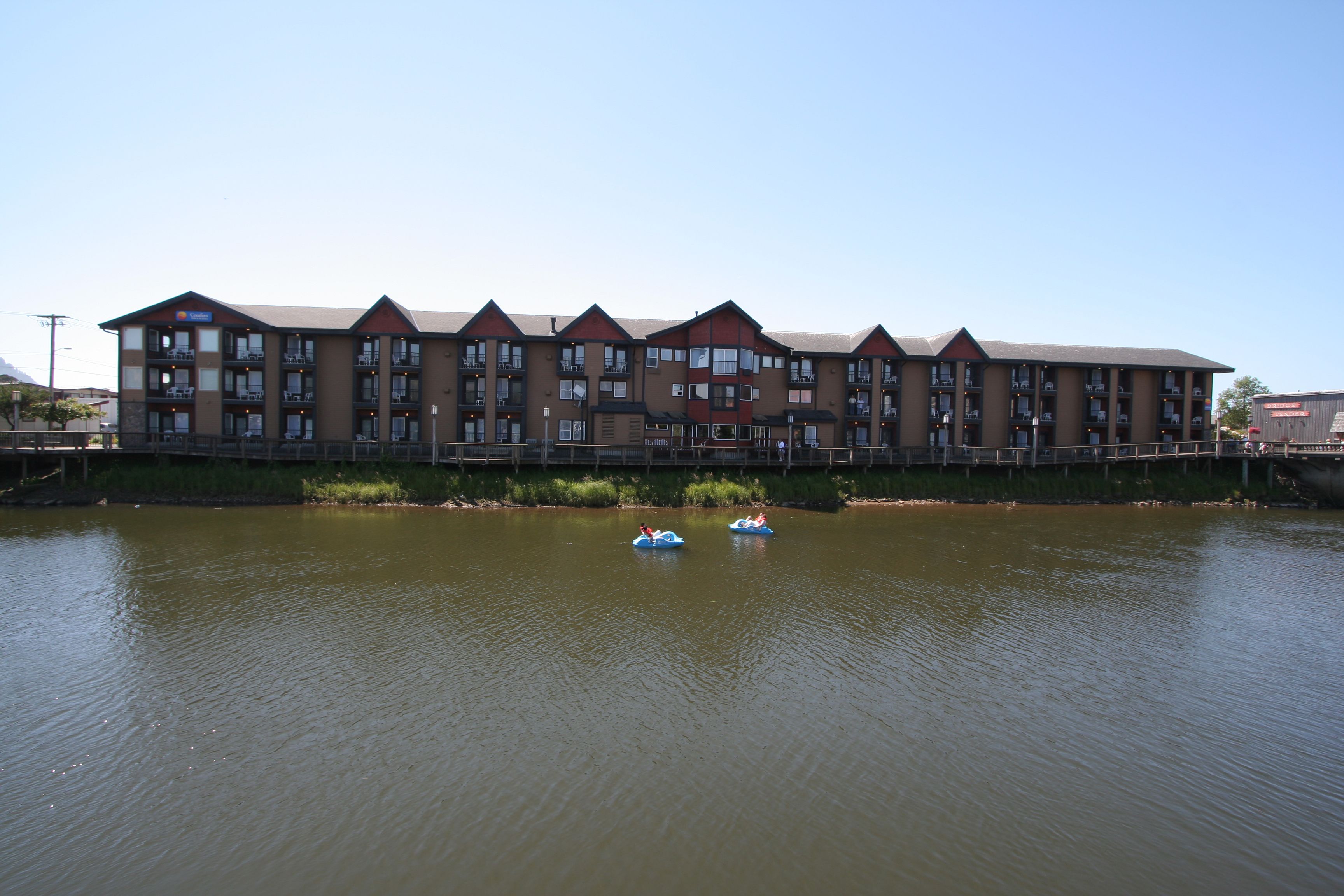 Un hôtel à plusieurs étages, doté de balcons, et situé en bord de rivière.