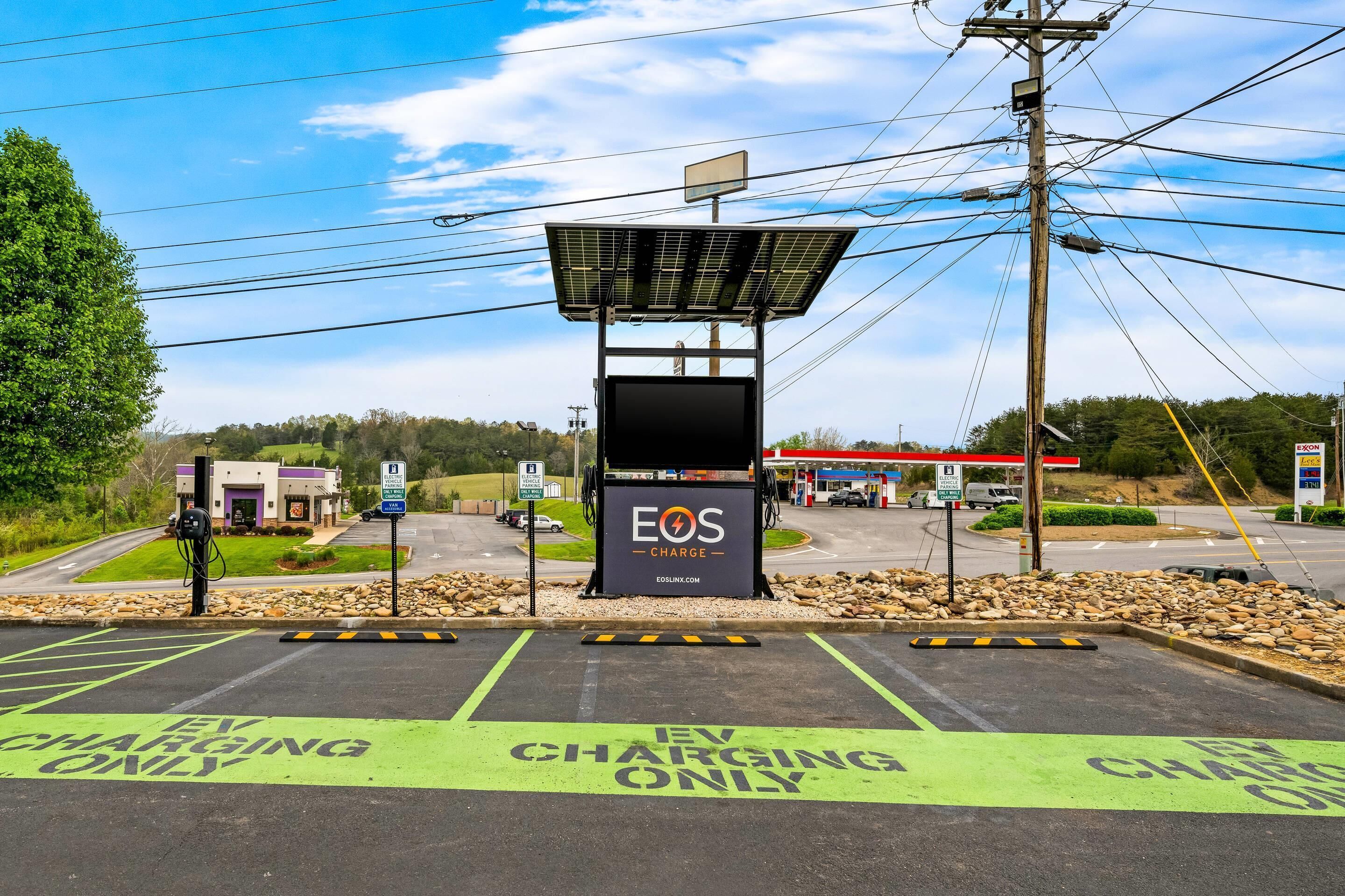 Una estación de carga con un letrero que dice "EOS CHARGE" y una estructura de paneles solares.