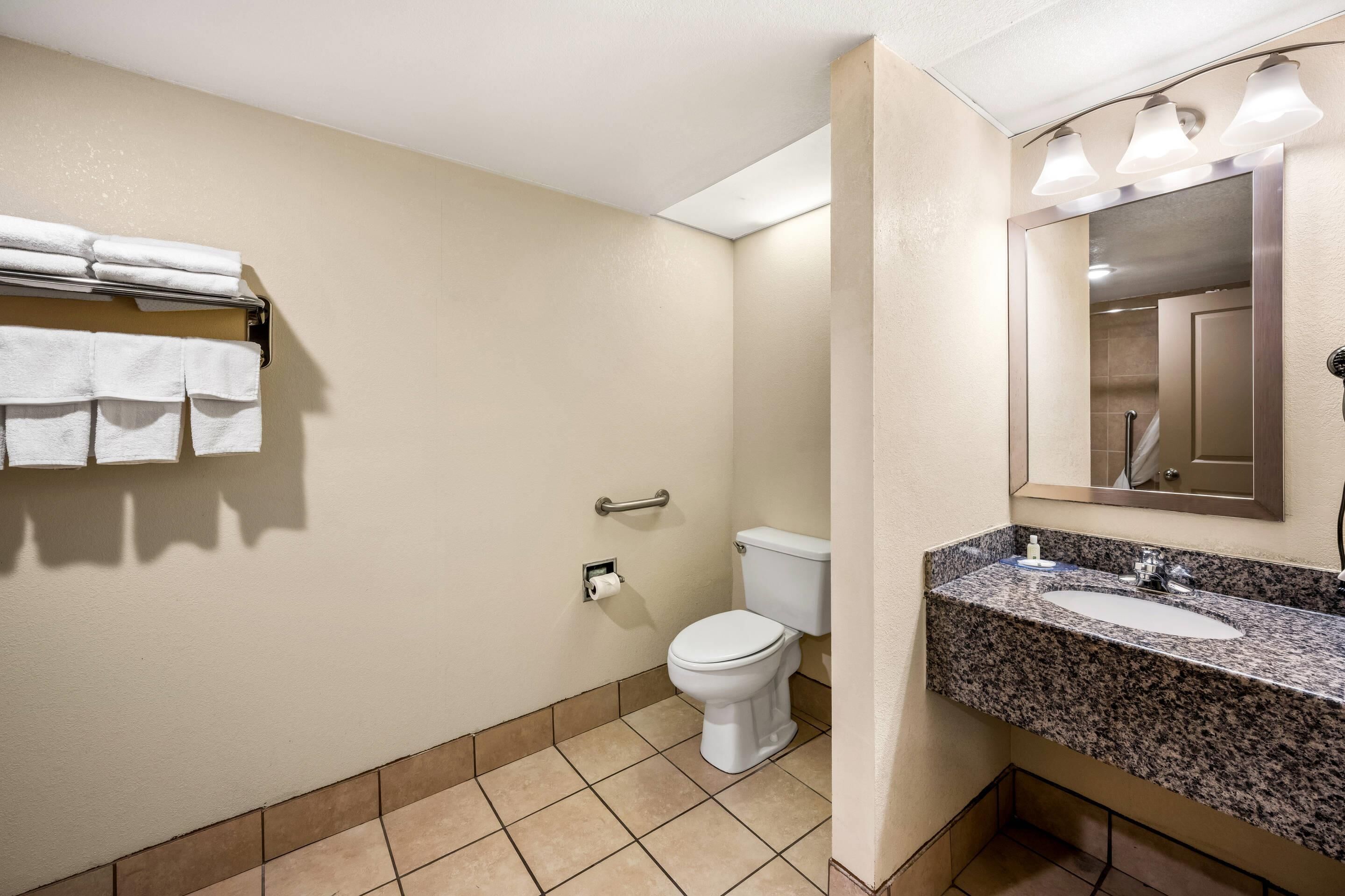 Un baño con inodoro, lavamanos y perchero para toallas.
