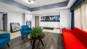 A reception area with a blue sofa, a red sofa, a round table with a plant, and a bulletin board with magazines. - Quality Inn Bulls Gap (Bulls Gap)