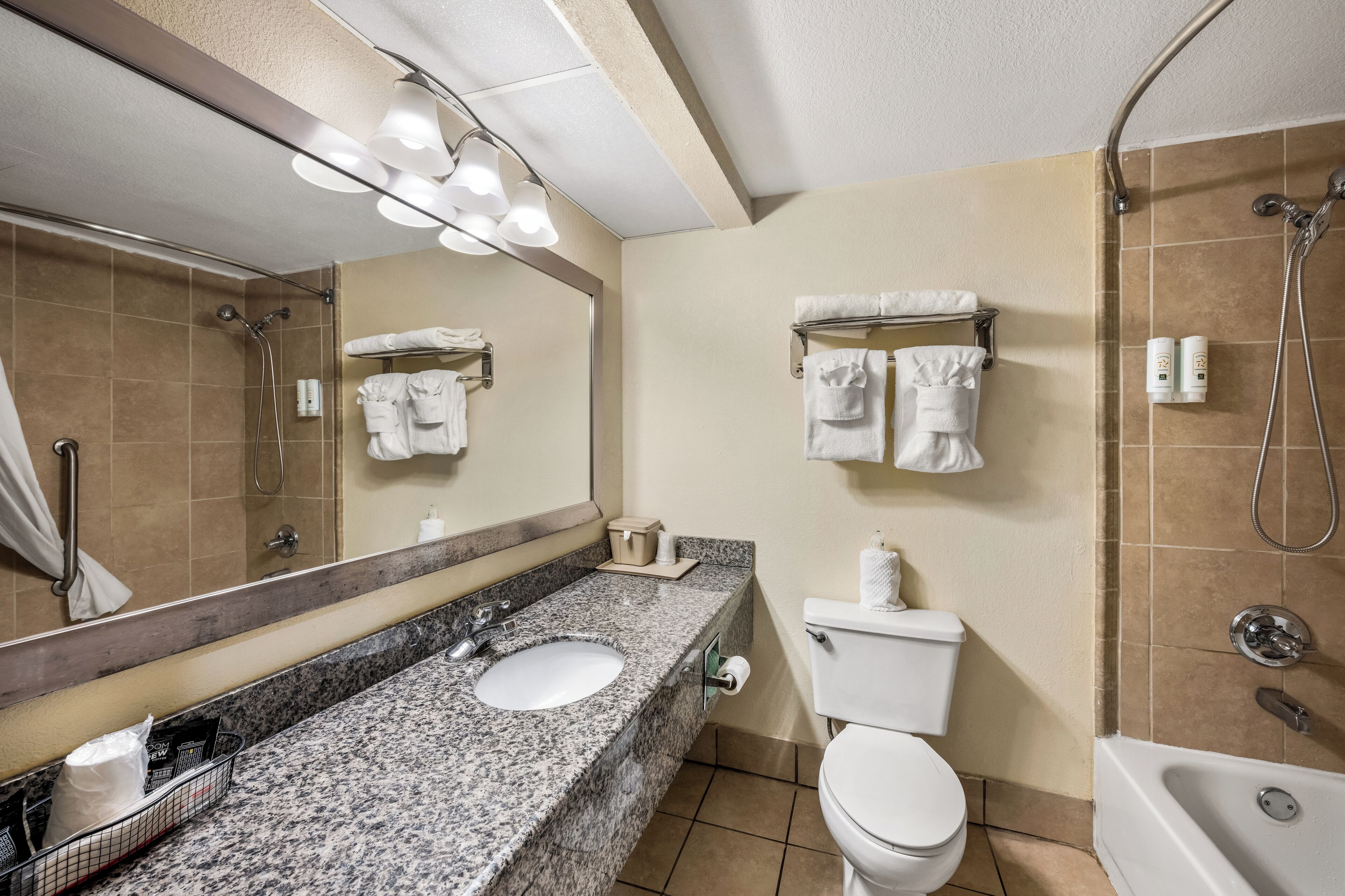 Un baño con lavamanos de granito, inodoro blanco y bañera.