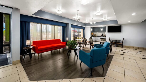 A modern living room with a red sofa, blue armchairs, a dining area, and a kitchen with a flat-screen TV. - Quality Inn Bulls Gap (Bulls Gap)