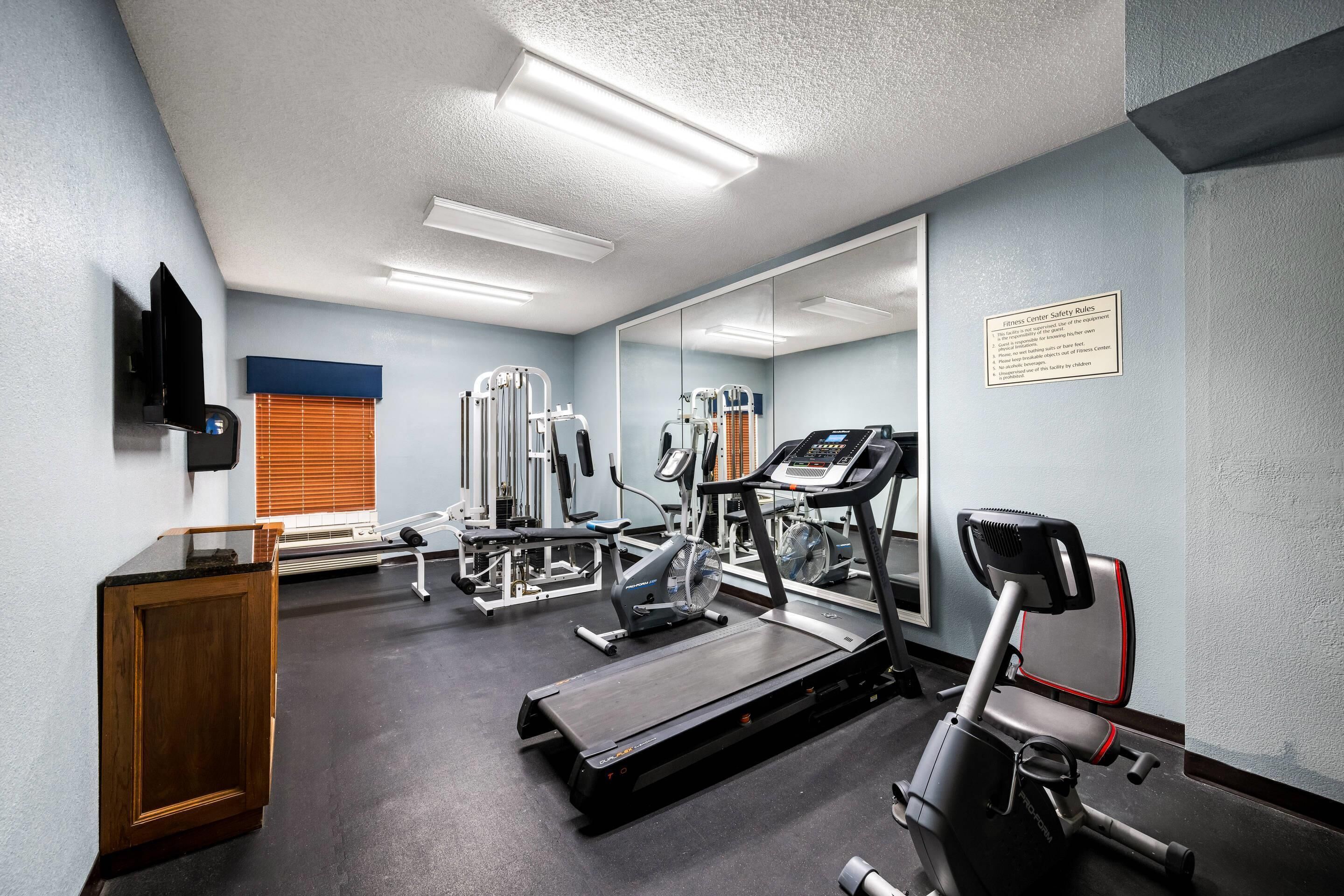 A fitness center with cardio machines, weight equipment, and a mirrored wall.