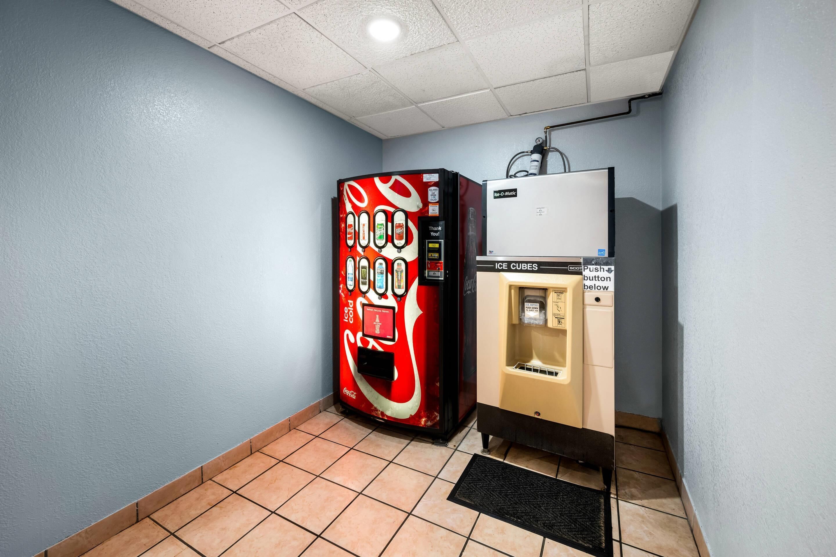 Una máquina expendedora con el logotipo de Coca-Cola, un botón para pedir hielo y un dispensador de agua.
