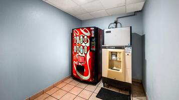 A vending machine with a Coca-Cola logo, a push button for ice cubes, and a water dispenser.
