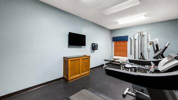 A gym with exercise equipment, a television, and a wooden cabinet.