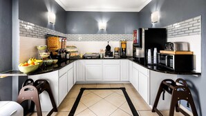 A compact kitchen with white cabinets, a black countertop, and a tiled backsplash. - Quality Inn Bulls Gap (Bulls Gap)