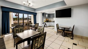 A dining area with tables and chairs, a kitchen area, and a large window with curtains. - Quality Inn Bulls Gap (Bulls Gap)